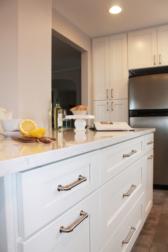 white kitchen island with granite countertop and kitchen cabinets