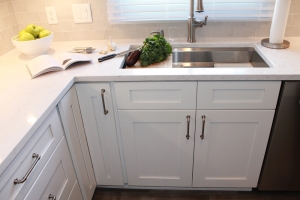 stainless steel sink with white kitchen cabinets and countertop
